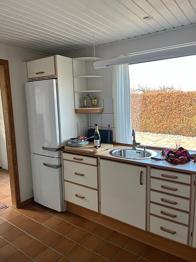 Køkken med skabe, bordplade, vask og hårde hvidevarer