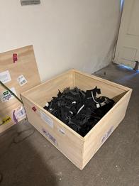 Trækasse med indhold af sorte plastdele