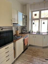 Hvidt vinkelkøkken med træbordplade og gaskogeplade